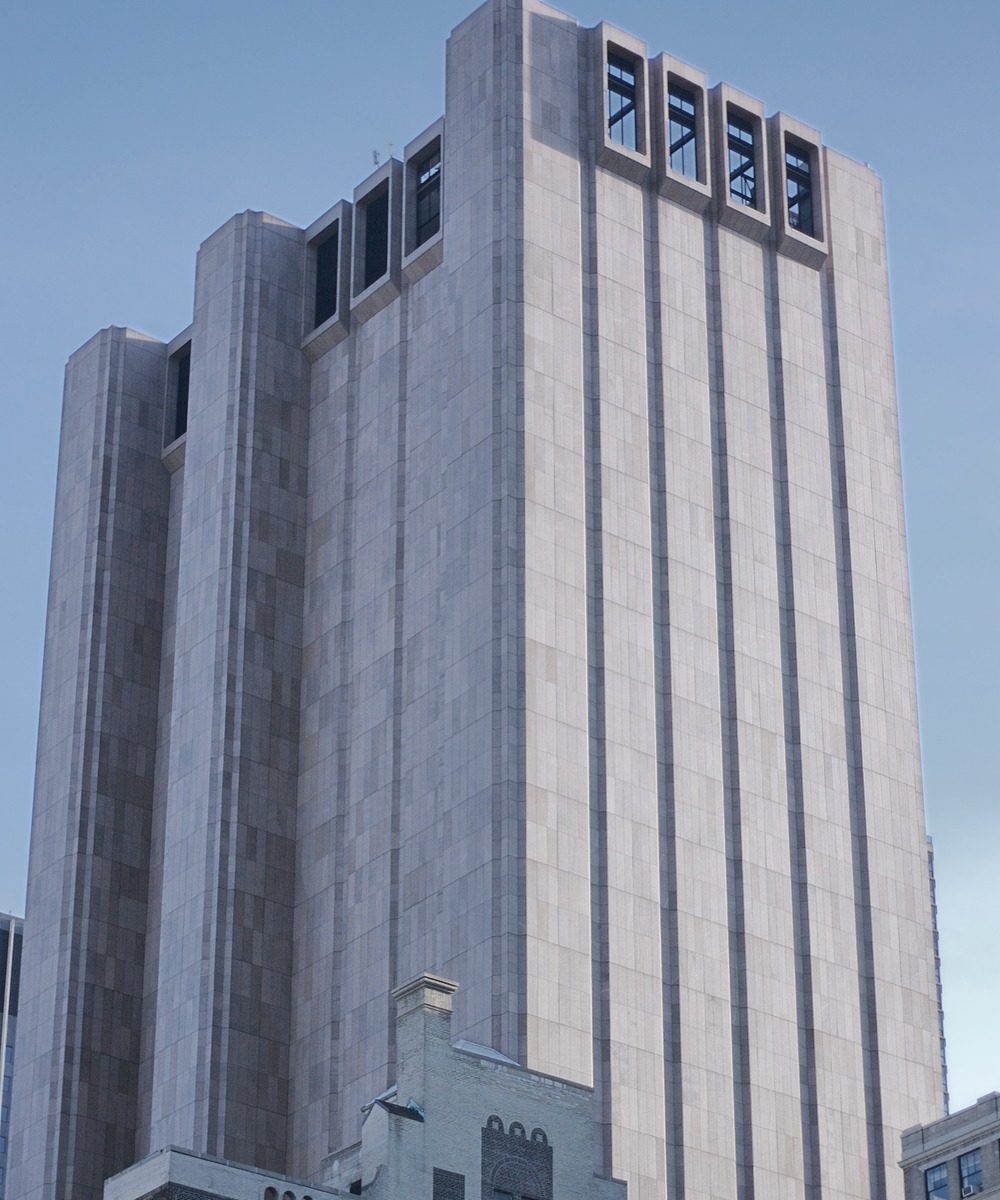The windowless granite facade of 33 Thomas Street (the AT&T Long Lines Building) rising above Lower Manhattan, with high mechanical exhaust openings near the roofline.